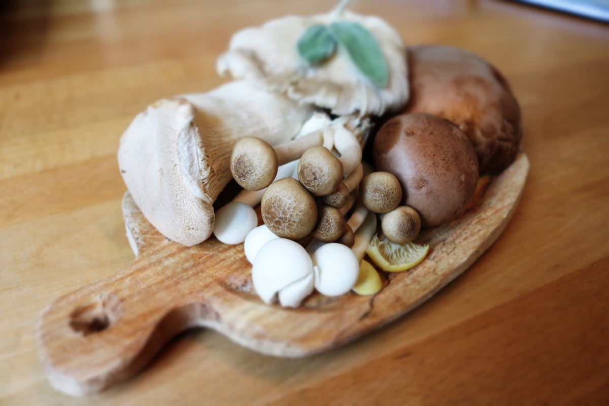 A variety of fresh mushrooms arranged on a rustic wooden board
