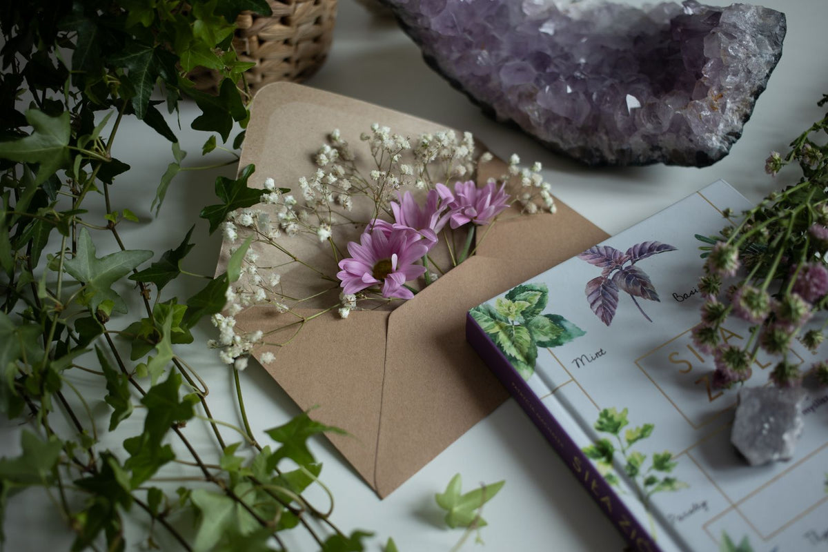 A calming flat lay of flowers, amethyst crystals, and a botanical book on a table