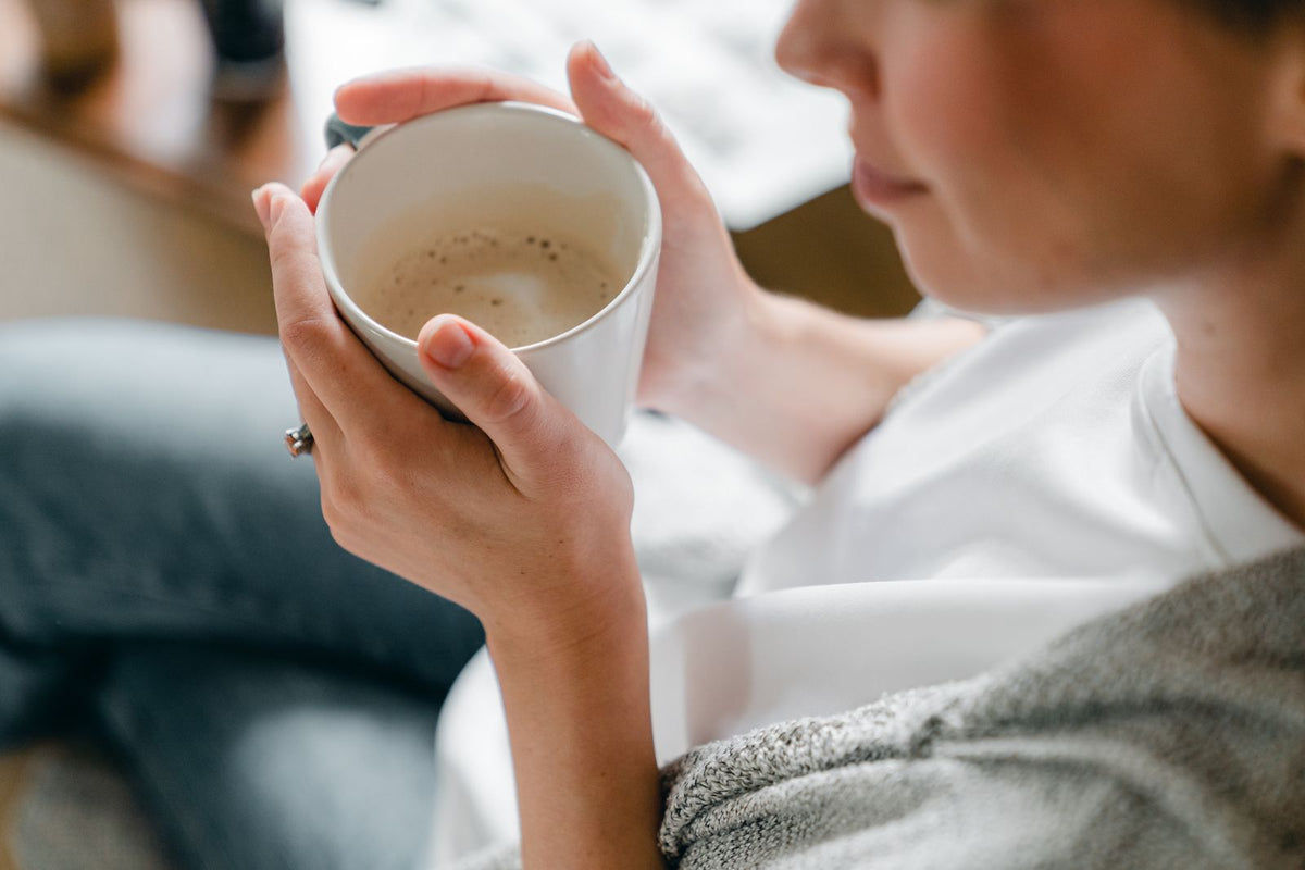 A woman relaxing at home, holding a warm cup of coffee with both hands