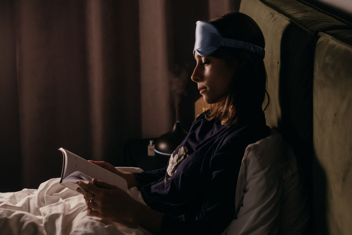 Woman holding a book and cup, reading in a calm evening setting