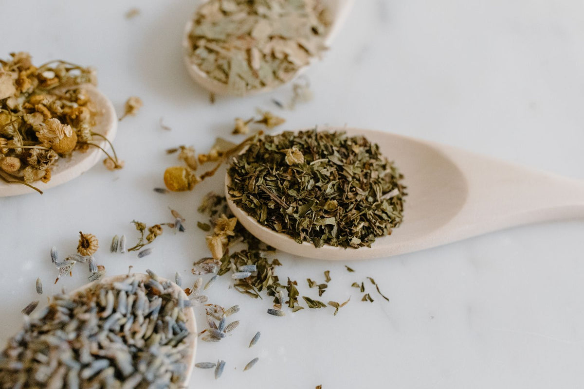 A collection of dried herbs on wooden spoons, used in natural remedies