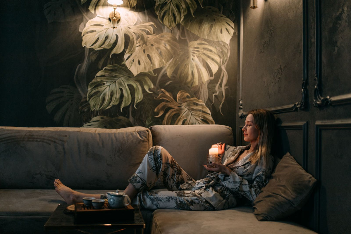 A woman relaxing on a sofa at home with a lit candle nearby